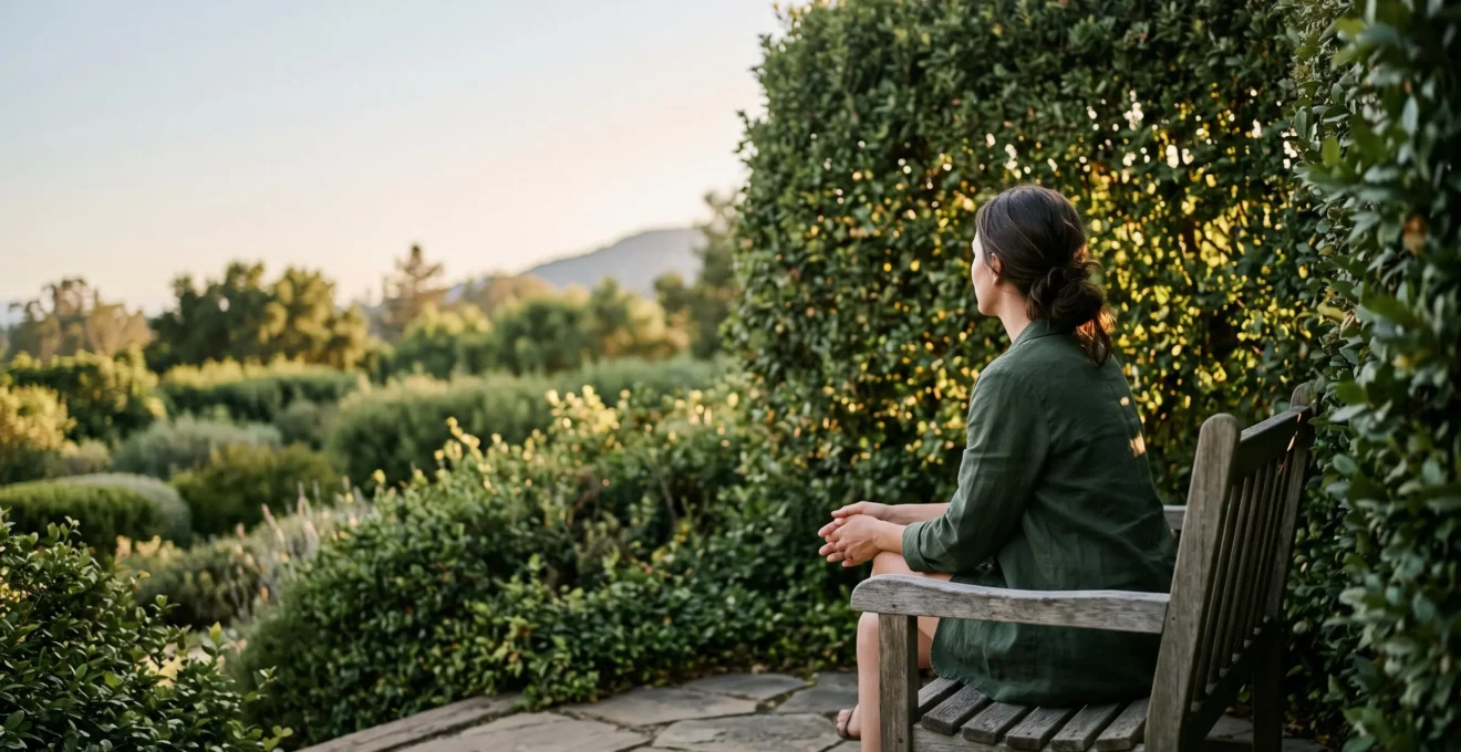 Coin de jardin apaisant avec siège en bois niché entre des plantations, offrant un refuge de décompression baigné de lumière douce